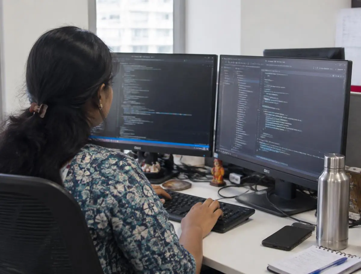 Software developer writing code on two monitors